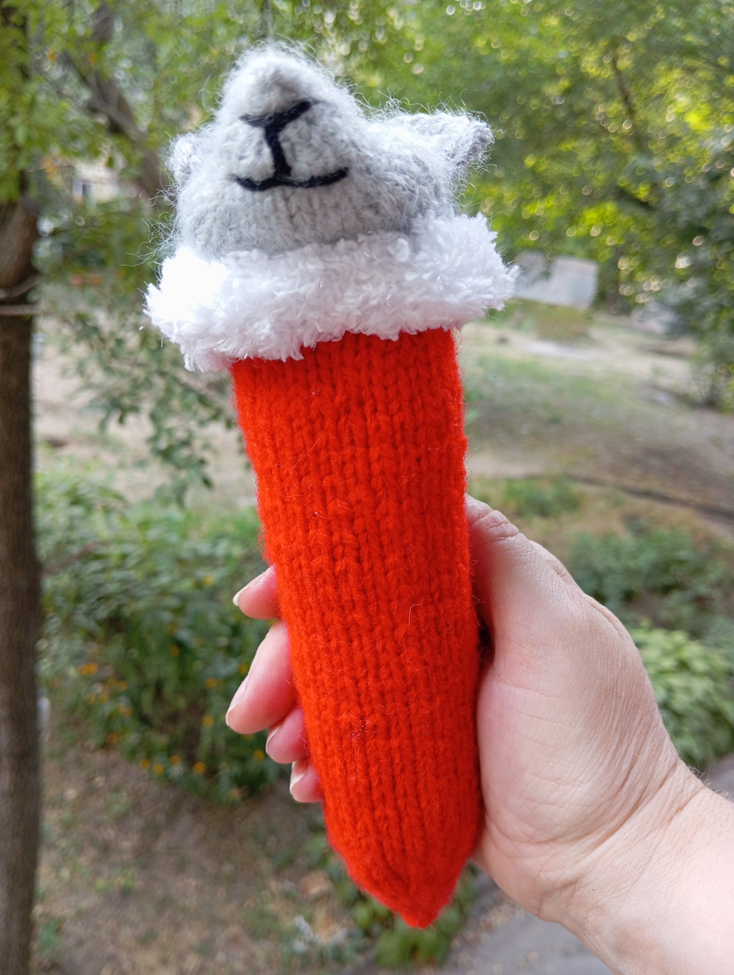 Knitted toy for a cat in the shape of a mouse wearing a Santa Claus hat